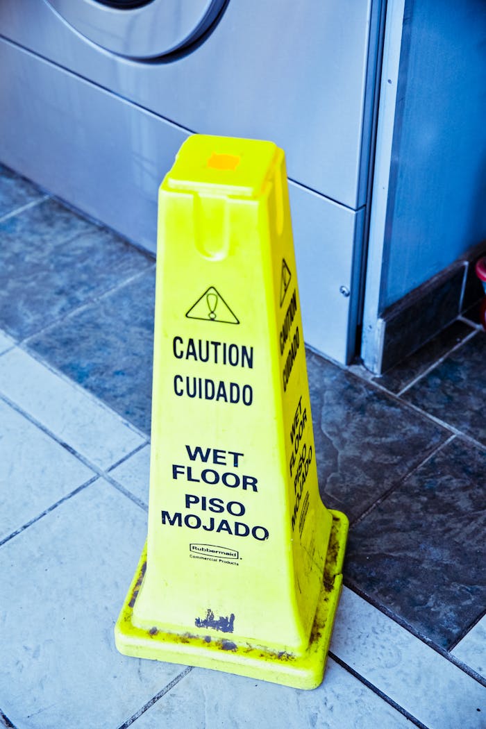 Bright yellow wet floor warning sign in a modern indoor space.
