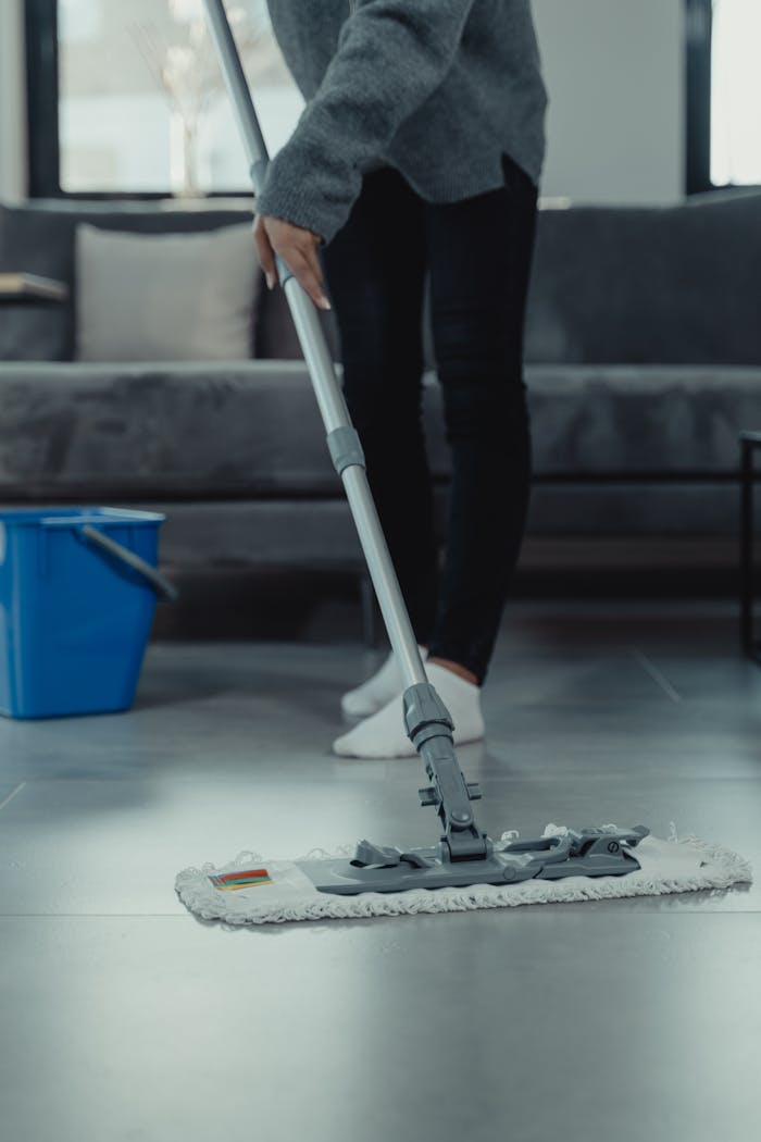 Close-up of person mopping a clean tile floor in a contemporary living room.